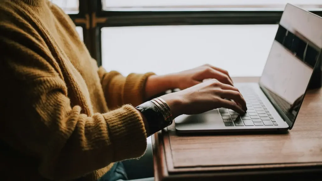 Étudiante qui travaille sur son ordinateur portable près d'une fenêtre