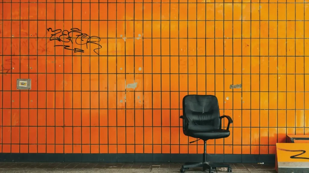 Chaise de bureau vide devant un mur de carrelage orange