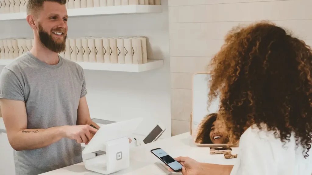 Vendeur souriant qui encaisse une cliente au comptoir