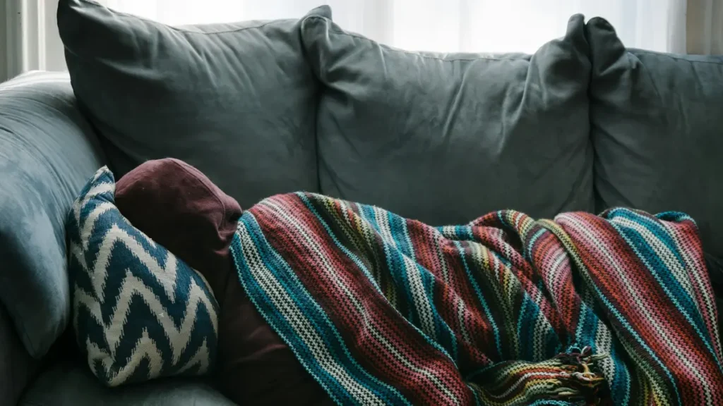 Personne allongée sous une couverture sur un canapé