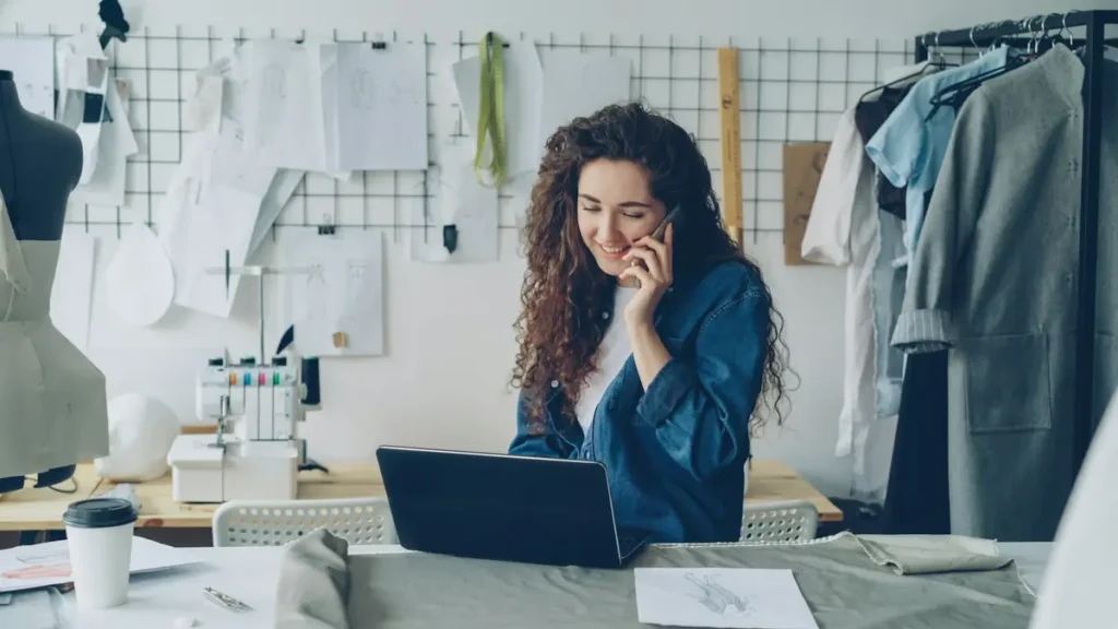 Créatrice qui téléphone devant son ordinateur dans son atelier