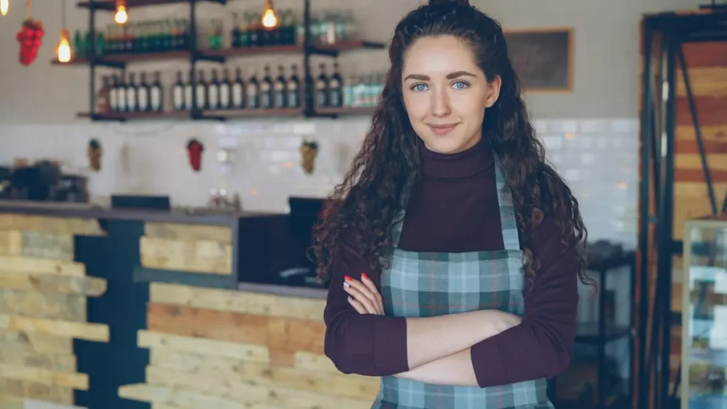 Gérante souriante, bras croisés, dans son café