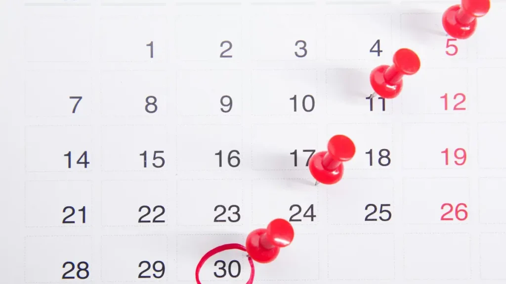Calendrier avec des punaises rouges sur plusieurs dates