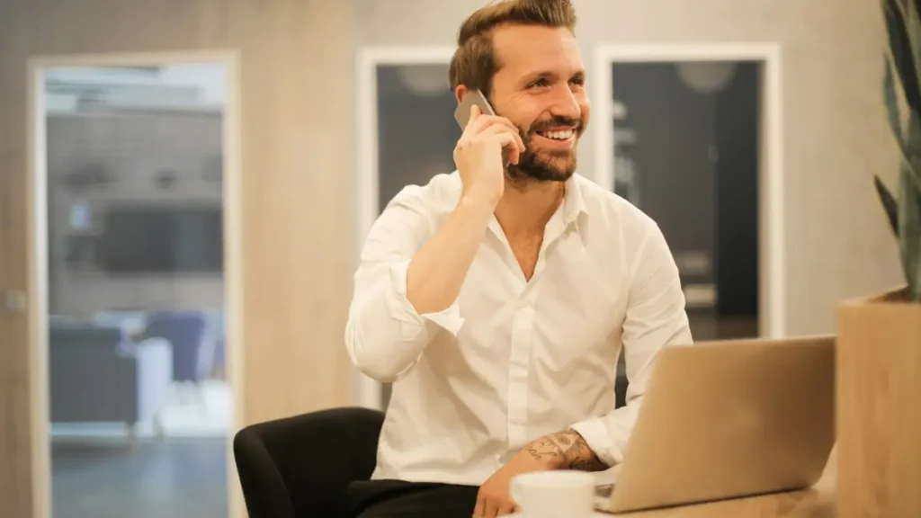 Homme souriant au téléphone devant son ordinateur