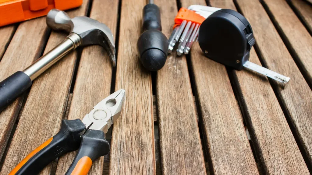 Outils posés sur une table en bois : marteau, pince, mètre