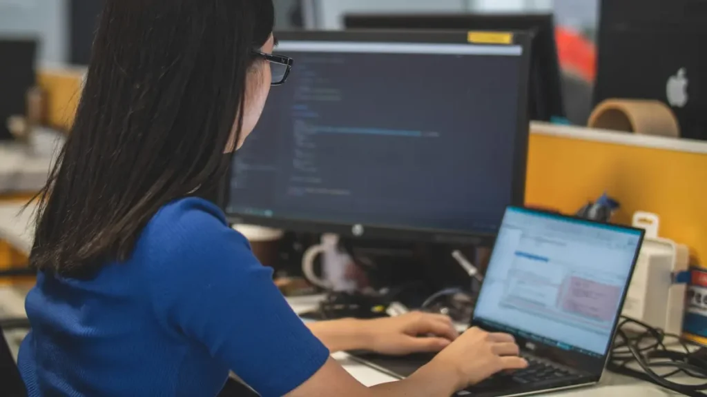 Femme qui travaille sur un ordinateur portable et un écran de code