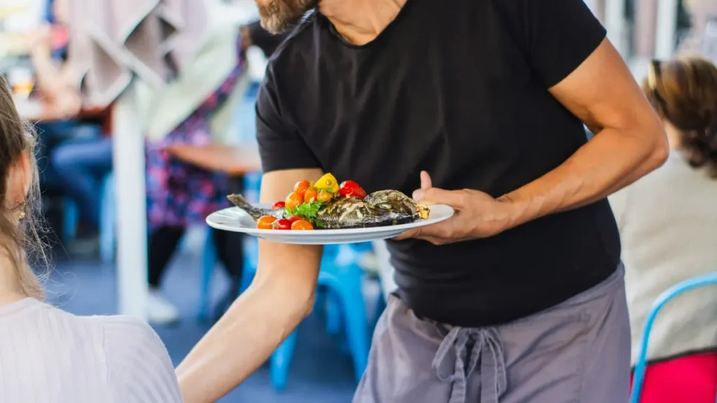 Serveur qui apporte une assiette à une table
