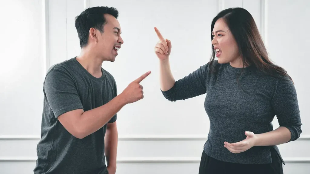Un homme et une femme qui se disputent en se pointant du doigt