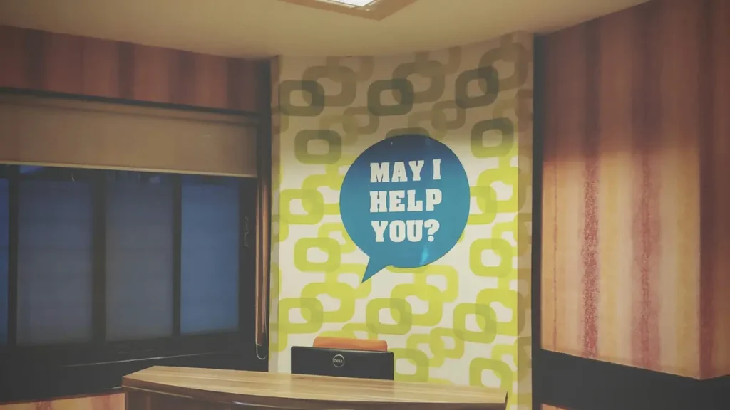 Comptoir d'accueil avec une affiche May I help you