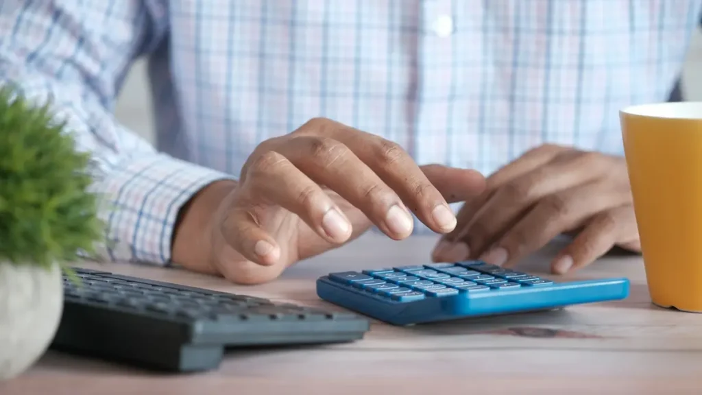 Mains qui utilisent une calculatrice sur un bureau