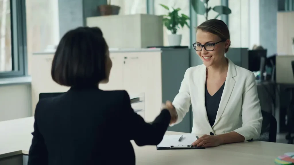 Deux femmes qui se serrent la main de part et d'autre d'un bureau