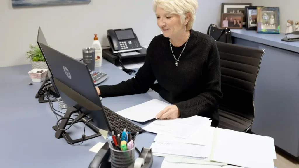 Assistante qui travaille à son bureau devant un écran et des documents