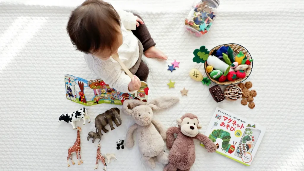 Jeune enfant qui joue avec des jouets et des peluches sur un tapis blanc