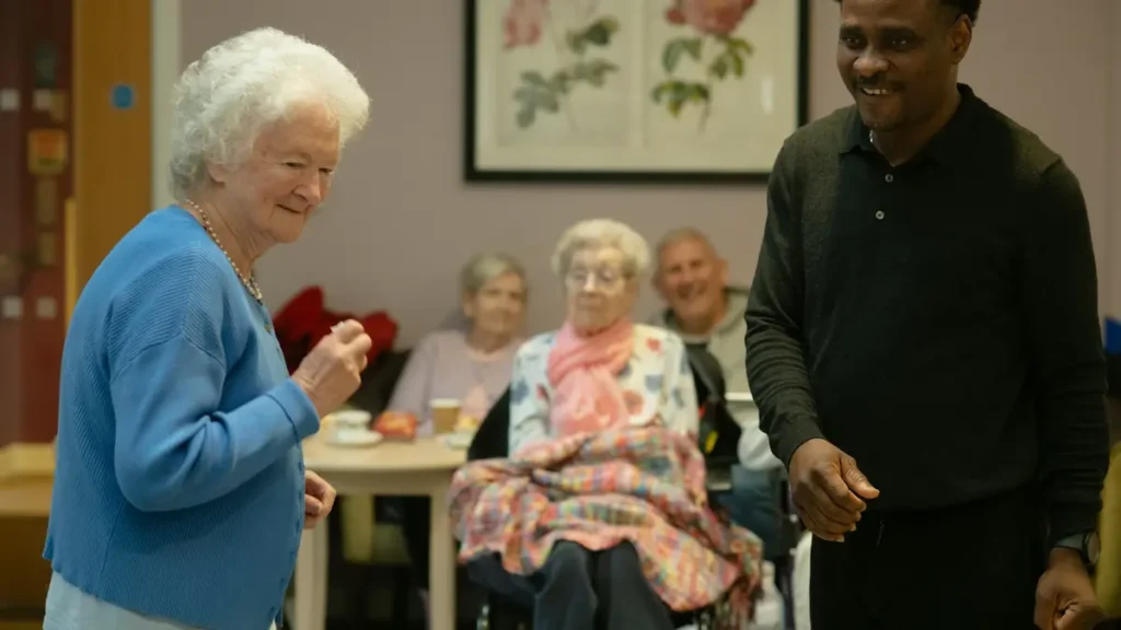 Accompagnant souriant avec des personnes âgées dans une salle commune