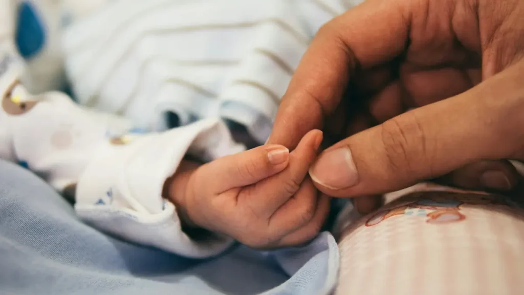 Main d'adulte qui tient le doigt d'un nouveau-né
