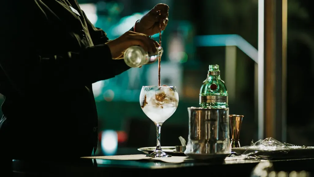 Barman qui verse un cocktail dans un verre à pied