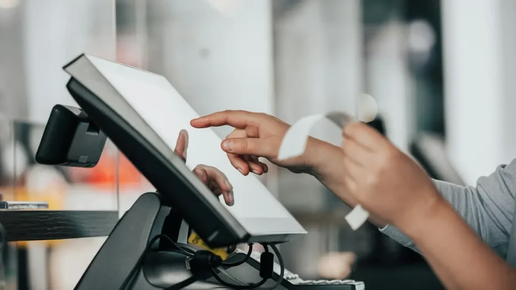 Main qui utilise l'écran tactile d'une caisse enregistreuse