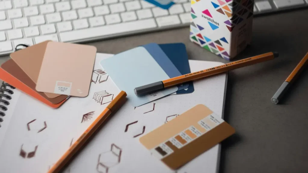 Nuanciers de couleurs, crayons et carnet posés à côté d'un clavier