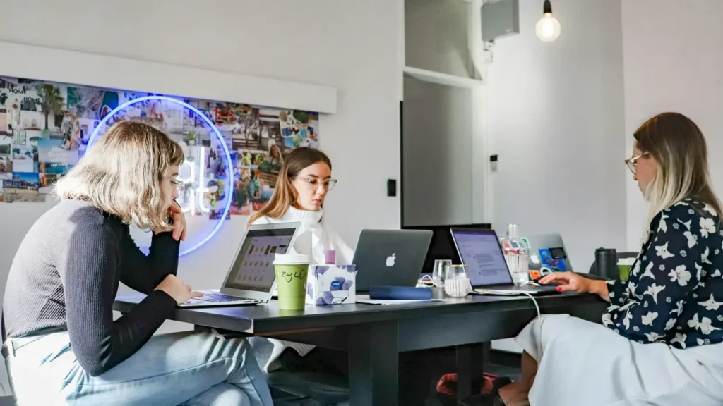 Trois collègues qui travaillent sur leurs ordinateurs dans un bureau lumineux