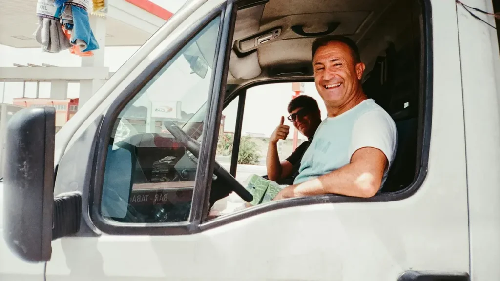 Chauffeur souriant au volant d'un utilitaire blanc