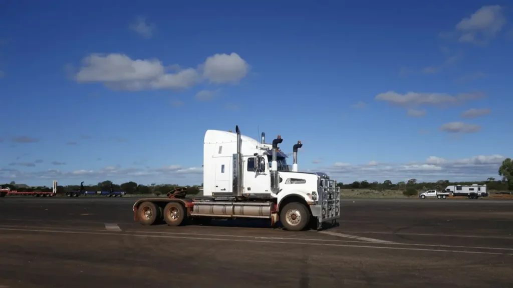 Camion semi-remorque blanc stationné sous un ciel bleu