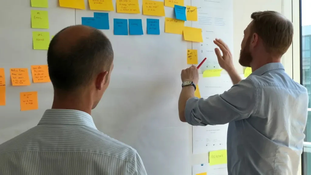 Deux collègues devant un tableau couvert de notes adhésives