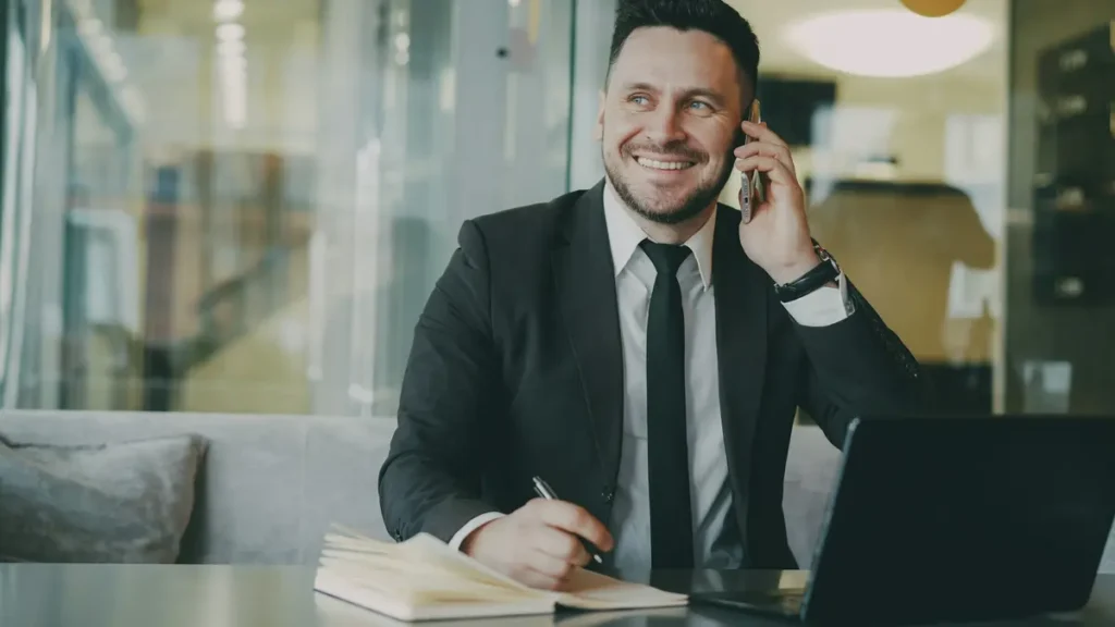 Commercial souriant en costume qui téléphone à son bureau