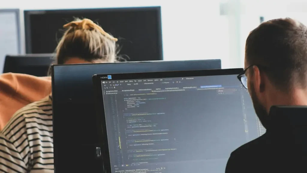Deux développeurs travaillent sur du code devant leurs écrans