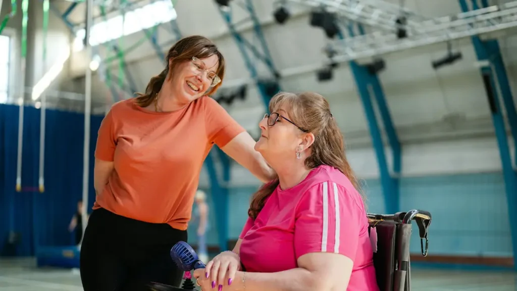 Accompagnante souriante auprès d'une femme en fauteuil roulant