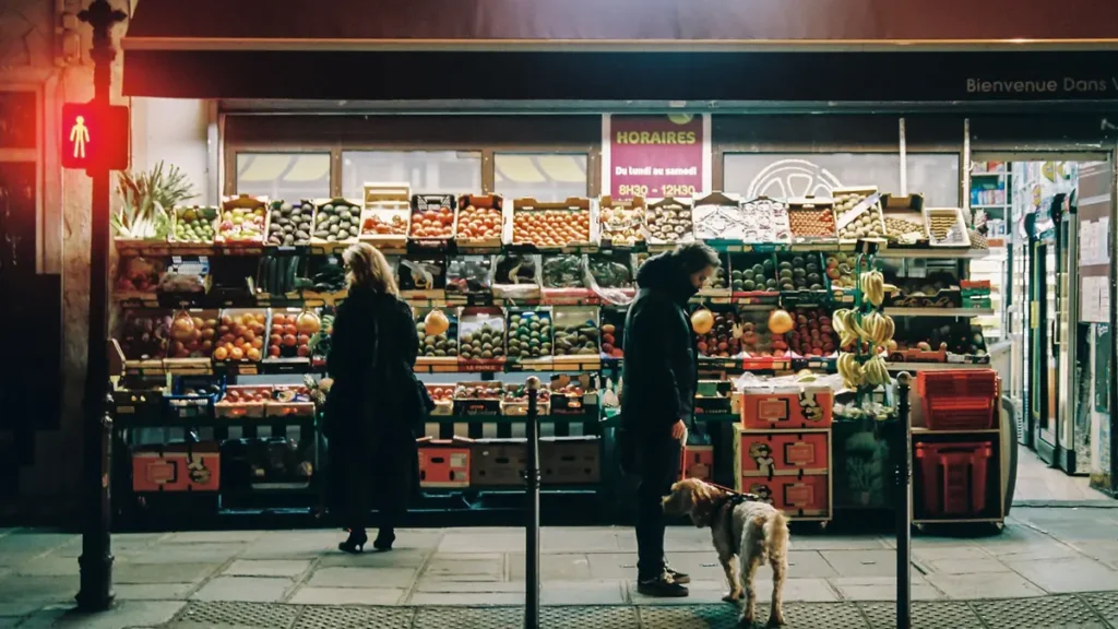 Épicerie de quartier éclairée le soir avec ses étals de fruits