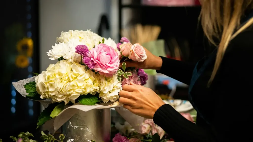 Fleuriste qui compose un bouquet de roses et d'hortensias