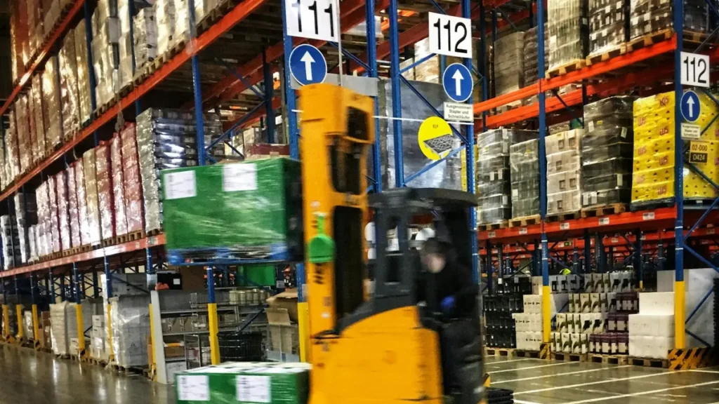 Chariot élévateur jaune entre des rayonnages d'entrepôt