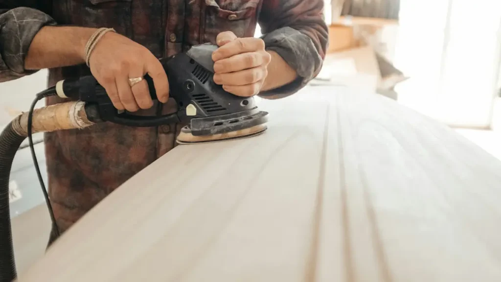 Menuisier qui ponce un plateau en bois