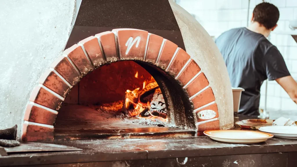 Pizzaiolo devant un four à bois en briques