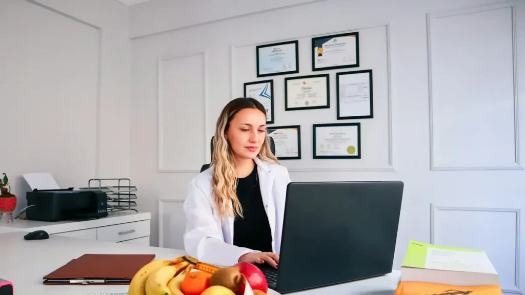 Secrétaire en blouse blanche qui travaille sur un ordinateur portable à son bureau