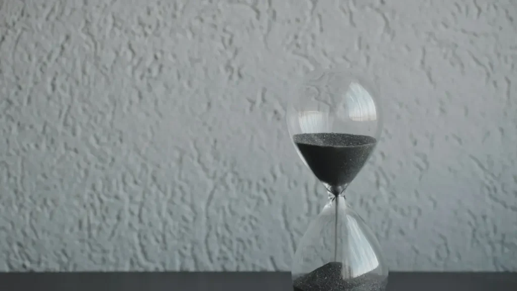 Sablier sur une table devant un mur gris