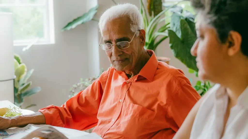 Homme âgé en chemise orange qui discute avec une accompagnante