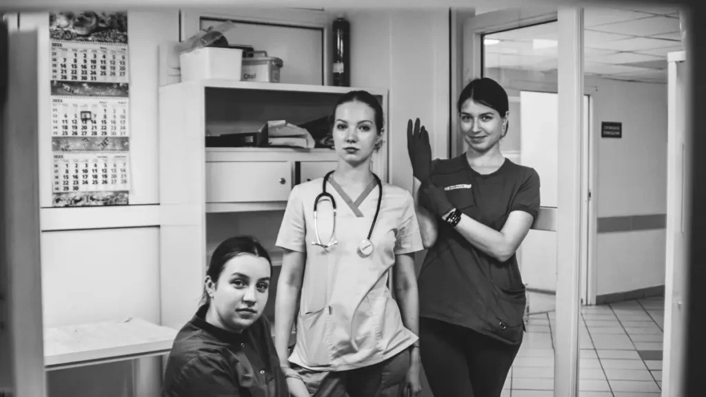 Trois soignantes en tenue dans un couloir d'hôpital