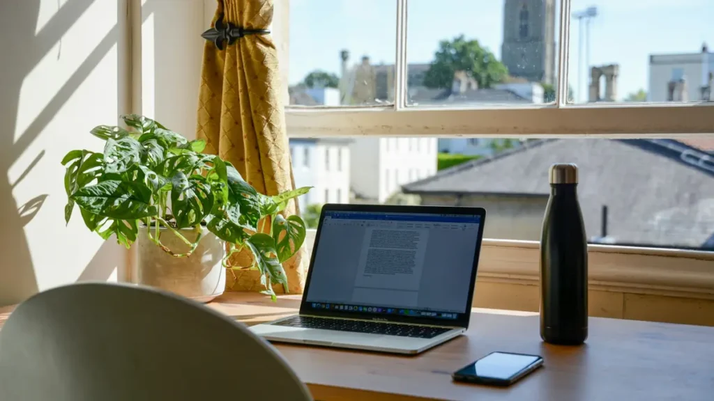 Ordinateur portable posé sur un bureau près d'une fenêtre