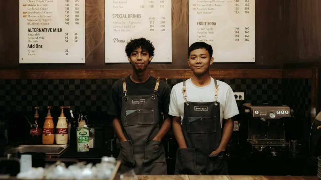 Deux jeunes baristas souriants derrière un comptoir