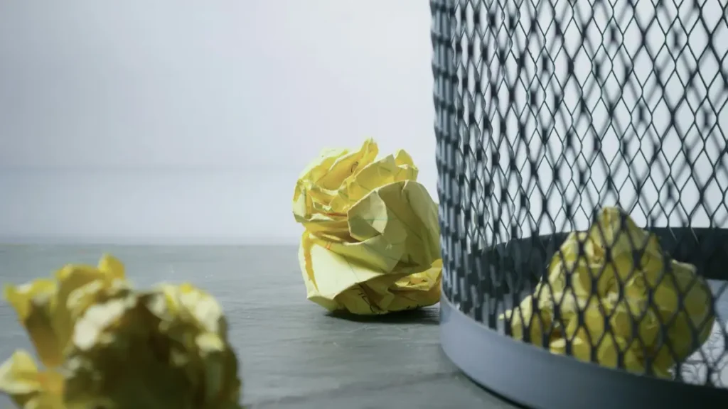 Boules de papier froissé jaune à côté d'une corbeille