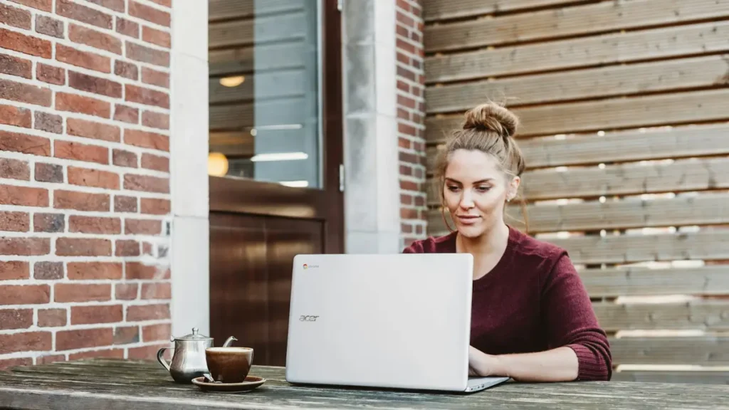 Étudiante qui travaille sur un ordinateur portable en terrasse
