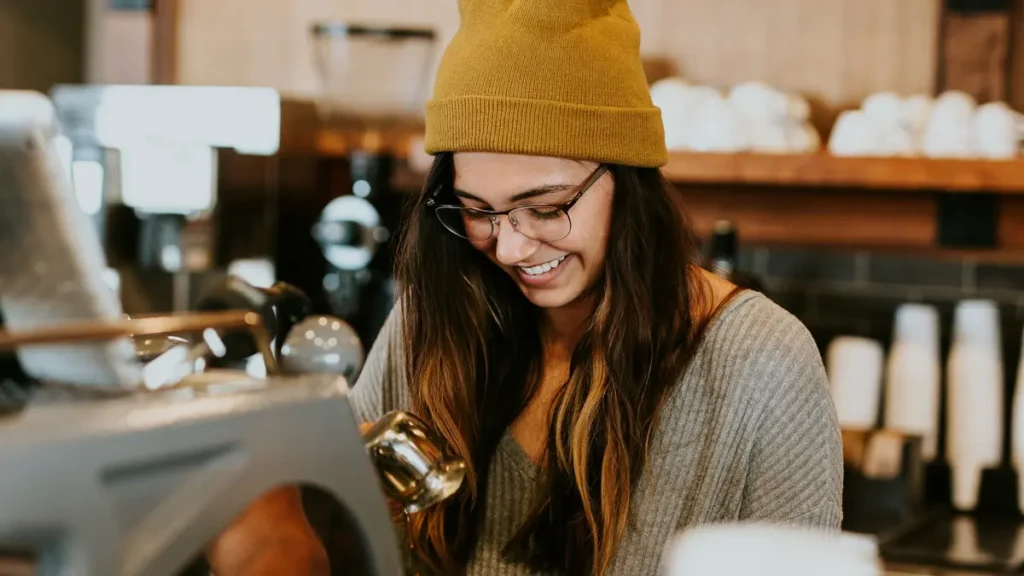 Étudiante souriante derrière le comptoir d'un café