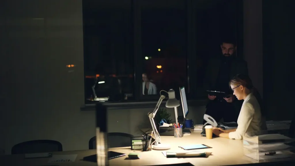 Salariés qui travaillent tard dans un bureau sombre