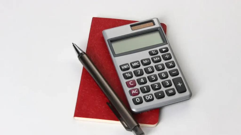 Calculatrice et stylo posés sur un carnet rouge