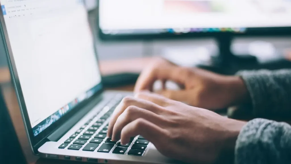 Mains qui tapent sur le clavier d'un ordinateur portable