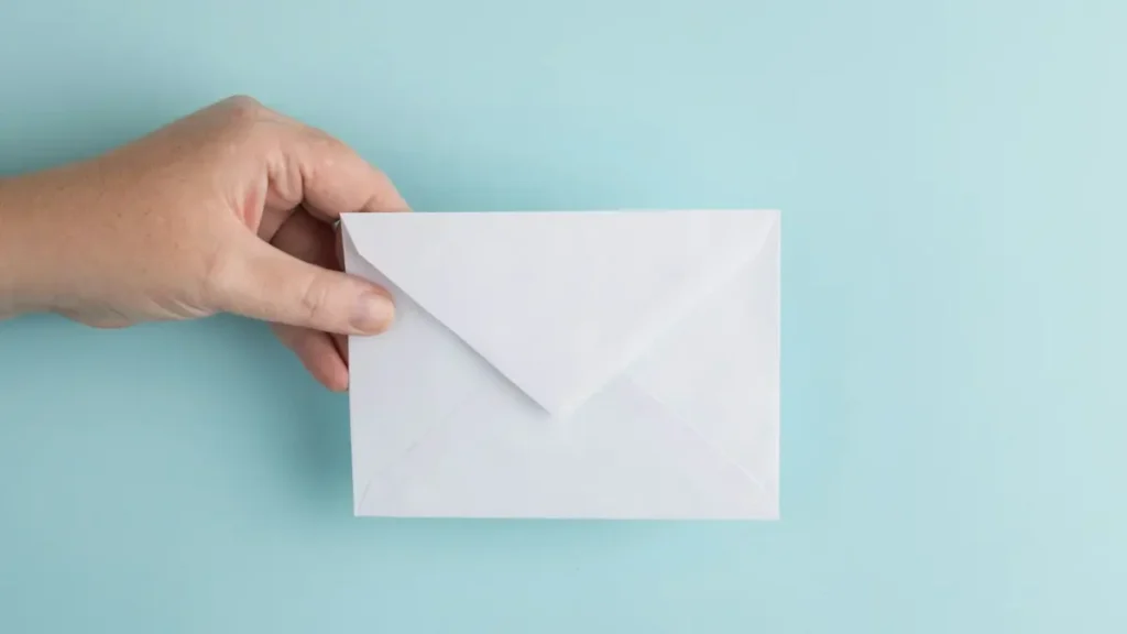 Main qui tend une enveloppe blanche sur un fond bleu