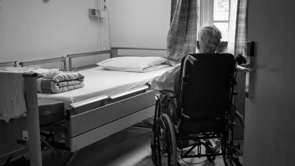 Chambre d'hôpital avec une personne âgée en fauteuil roulant
