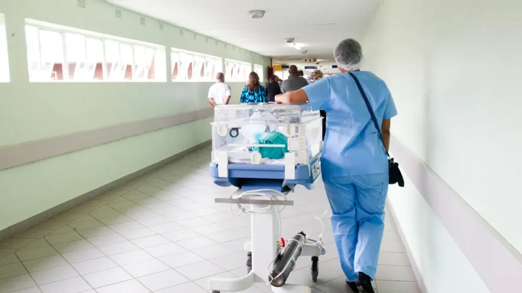 Soignante qui pousse une couveuse dans un couloir d'hôpital
