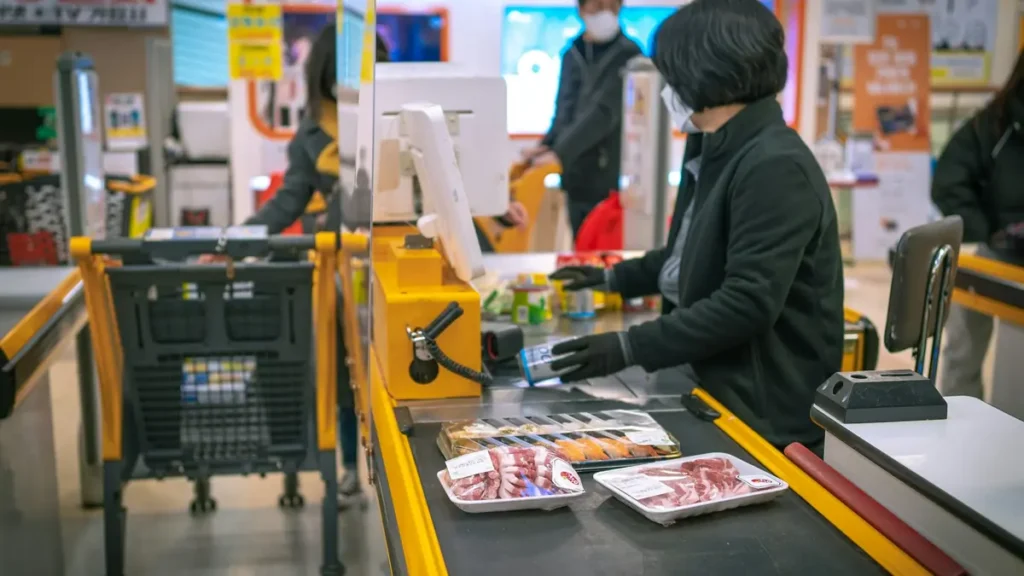 Caissière qui scanne des articles à une caisse de supermarché